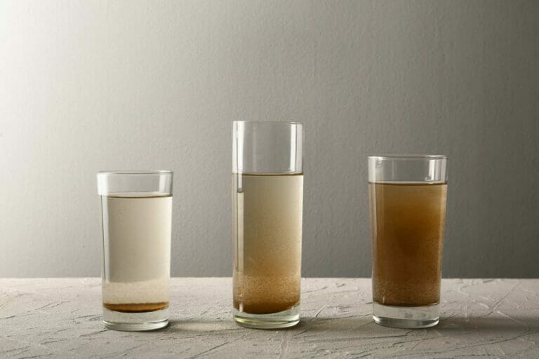 Multiple glasses filled with water, showing various levels of cloudiness and impurities, emphasizing the importance of improving water quality in your home.