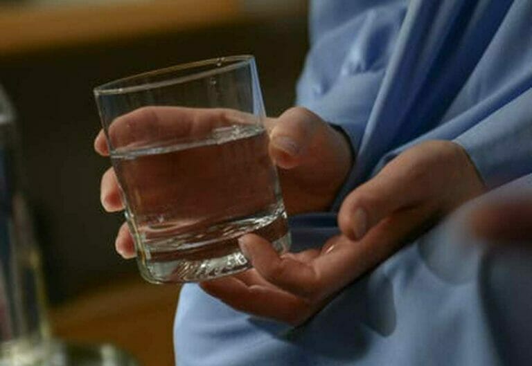 A photo of a person holding a glass of clear water in their hands, illustrating the importance of addressing hard water issues for a better quality of life and maintaining a healthy home.