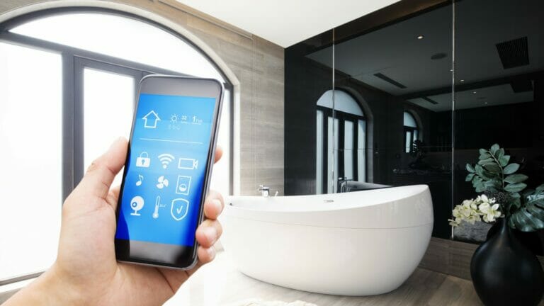 A mobile phone displaying a smart home application is placed on a sleek countertop in a modern bathroom, symbolizing the integration of technology in contemporary plumbing solutions.