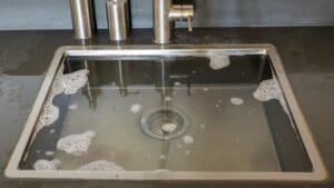 Close-up of a partially clogged kitchen sink with soapy water residue, highlighting the need for drain cleaning services in Rockwall, TX