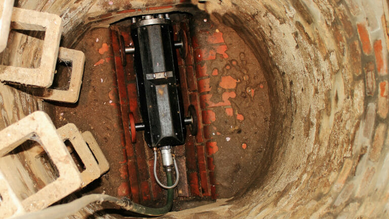 Close-up view of a specialized sewer camera equipment inside a drain, capturing the condition of the sewer line with detailed brickwork and sediment visible, exemplifying advanced plumbing diagnostic methods in Rockwall, TX.