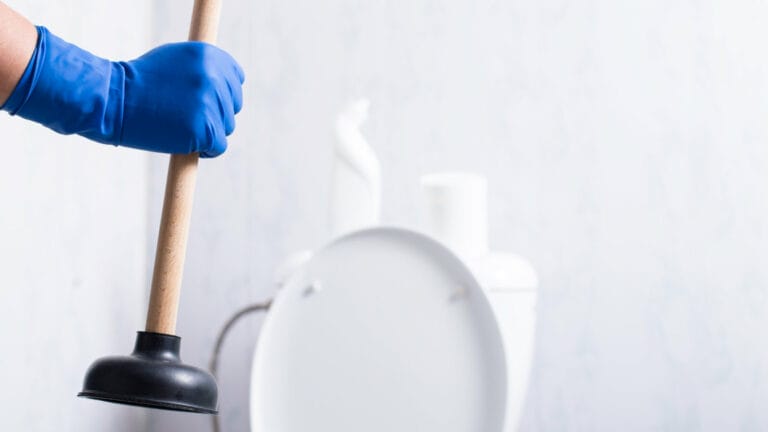 Hand in a blue glove holding a plunger, ready to unclog a toilet in Rockwall, TX.