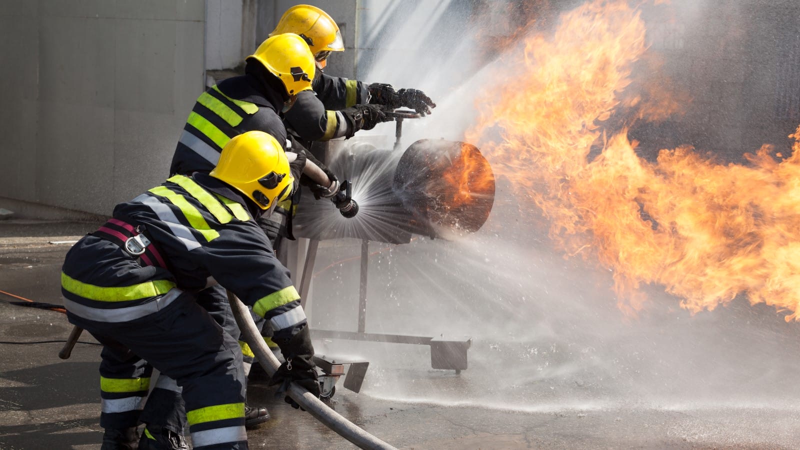 Firefighters in protective gear actively working to extinguish a gas fire, illustrating the dangers associated with gas leaks and the importance of proper detection and safety measures in homes