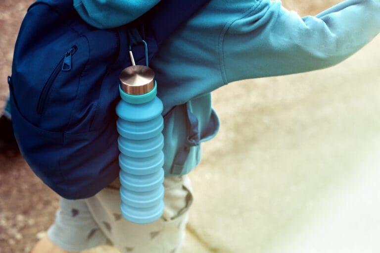 Reusable blue eco friendly water bottle on child's backpack.