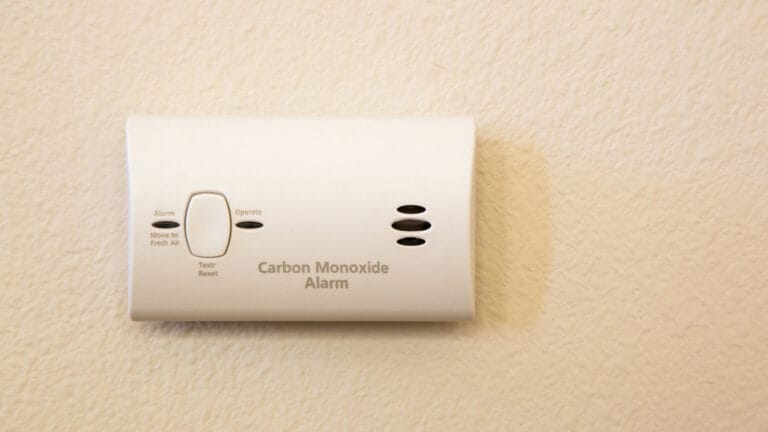 A carbon monoxide detector mounted on a home wall is essential for monitoring CO levels to ensure household safety, as discussed in the article on the necessity and quantity of CO detectors.
