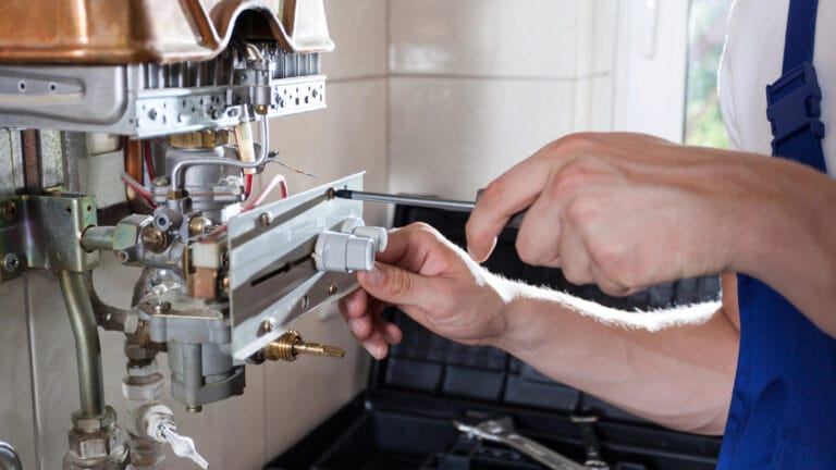 A professional technician adjusting a component on a gas water heater, performing essential maintenance to ensure efficient operation.