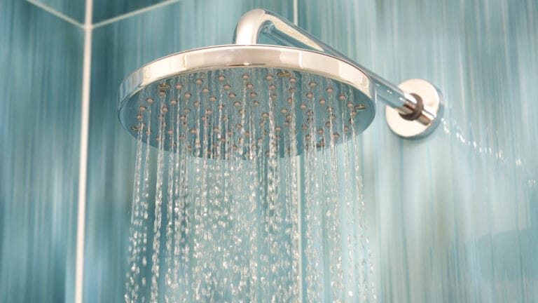 Modern overhead showerhead with water streaming down in a contemporary bathroom, reflecting plumbing innovation and eco-friendly technology trends for homeowners in 2024