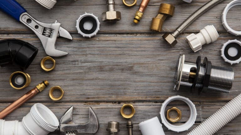 Assortment of plumbing tools and fittings including wrenches and pipes for a guide on what to know about plumbing.