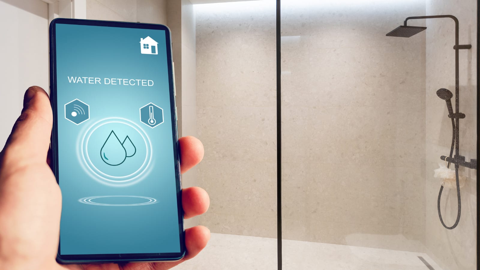 Hand holding a smartphone with a 'Water Detected' alert on the screen, indicating smart home technology integration in a modern bathroom setting.